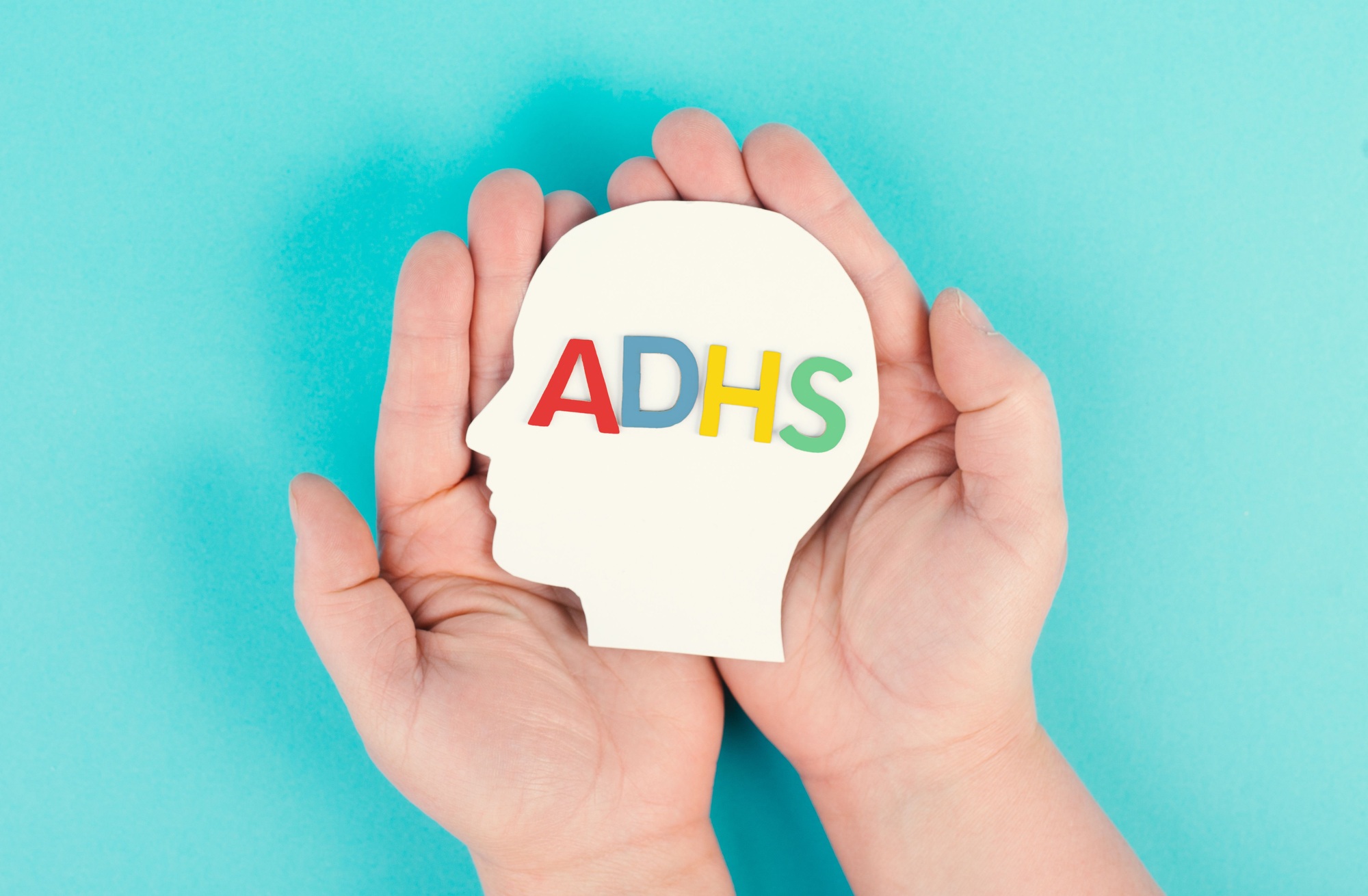 Hands holding a head with the german word ADHS which means attention deficit hyperactivity disorder
